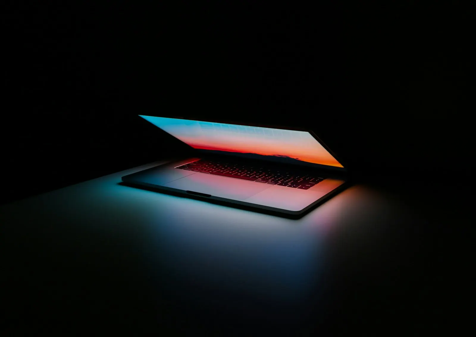 Laptop glowing in a dark room, suggesting software working quietly in the background