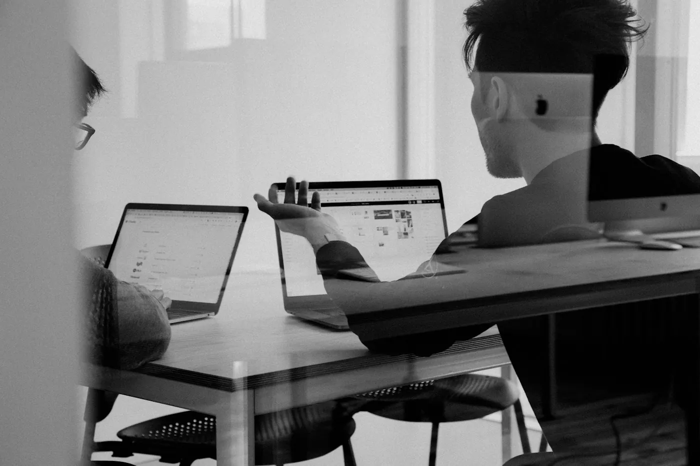 Team members working on laptops at a shared desk